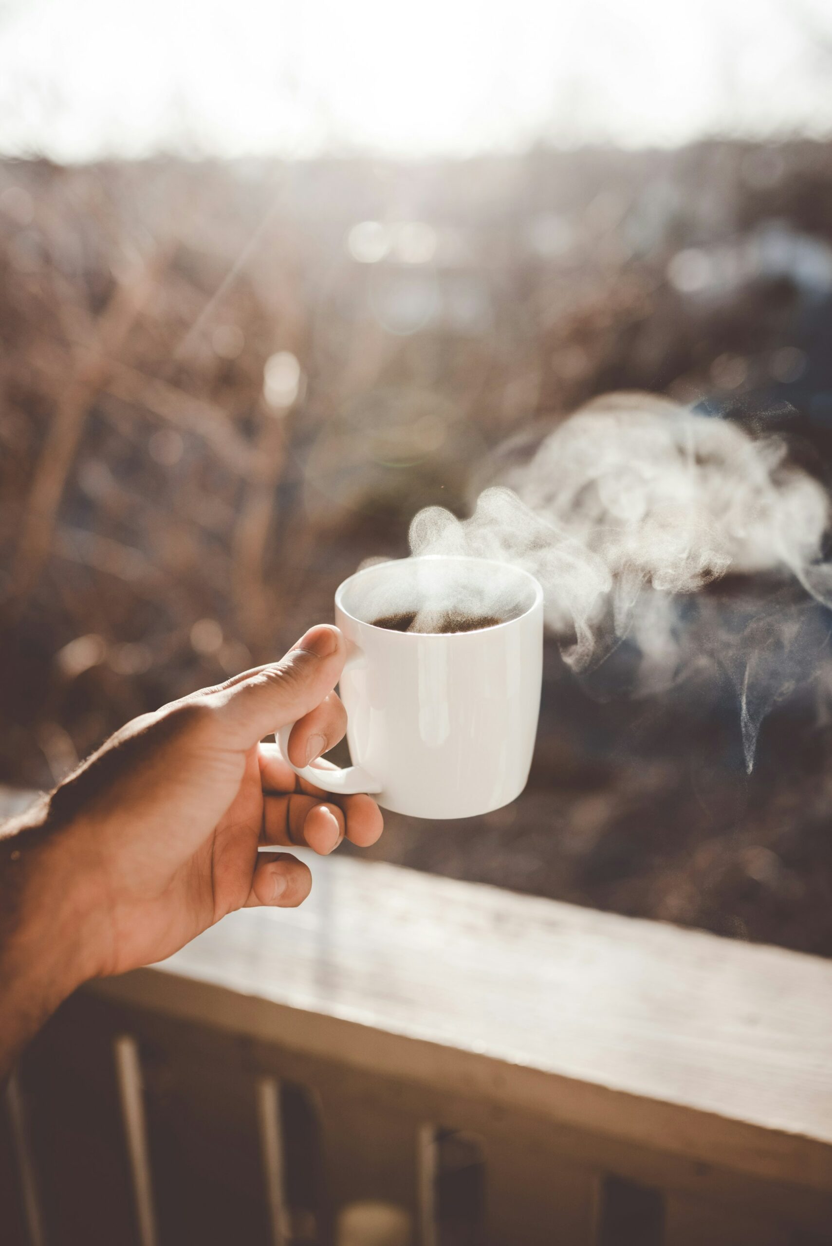 Hand holding mug of coffee outside