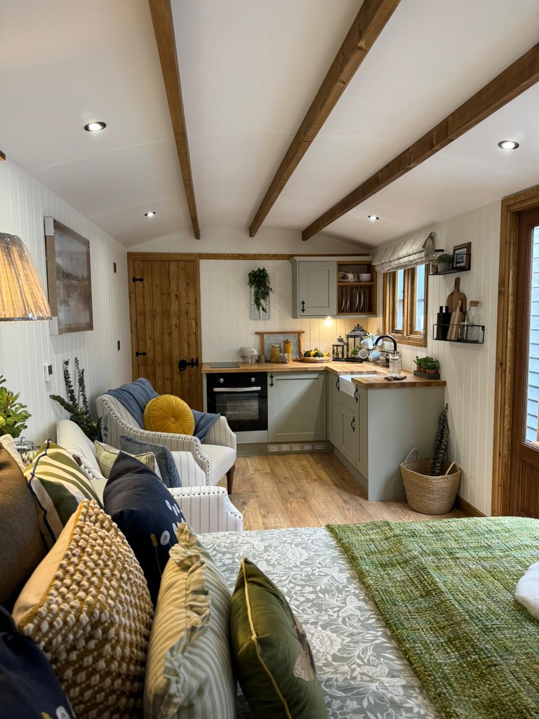 The interior of a shepherd's hut decorated in cream and green furniture