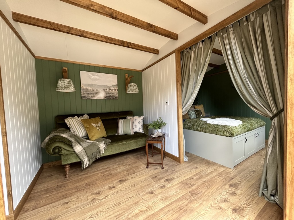 Photo of sofa and bedroom with curtain divider in the new Dorset shepherd's hut