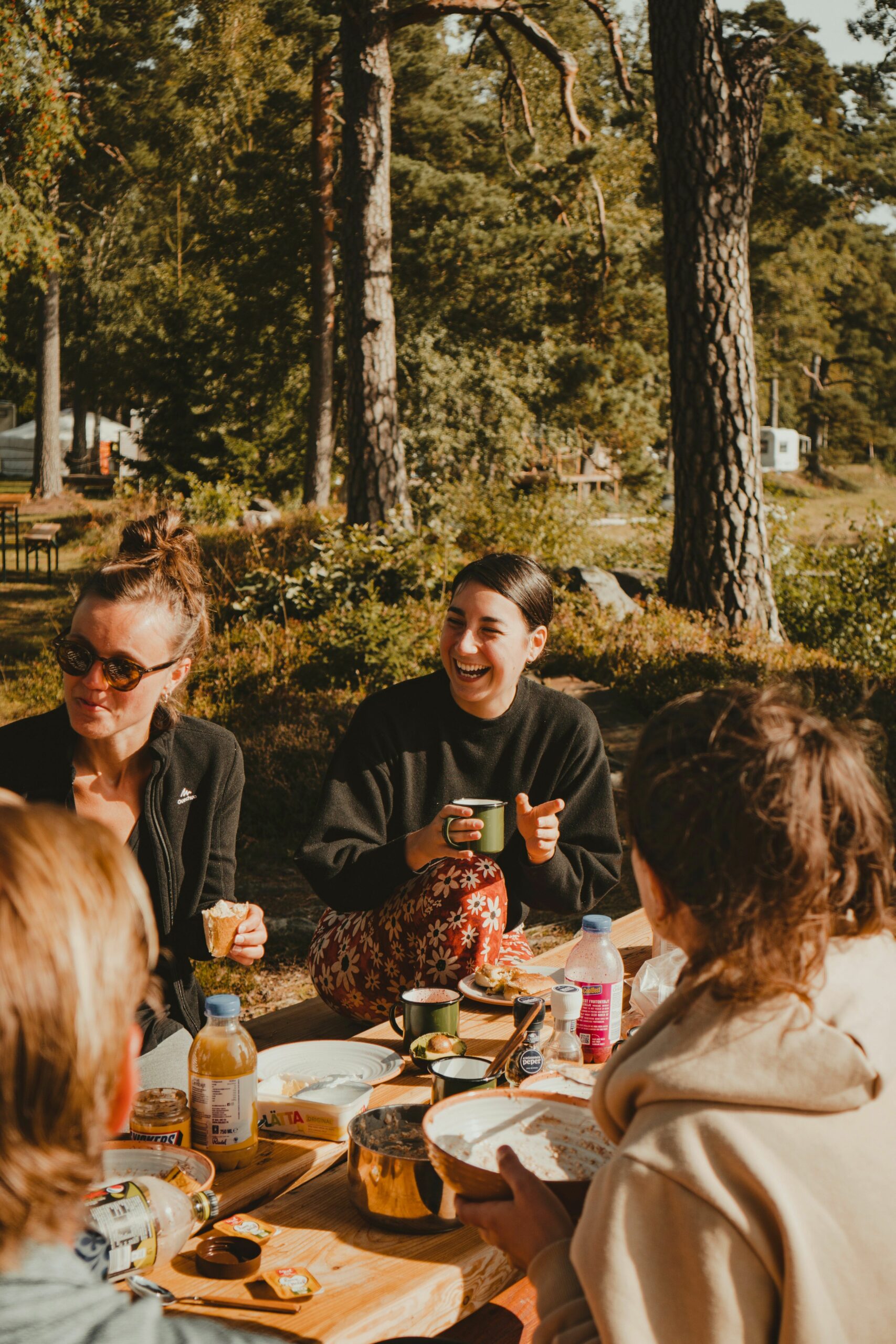 Laughing women sitting around table in glamping site